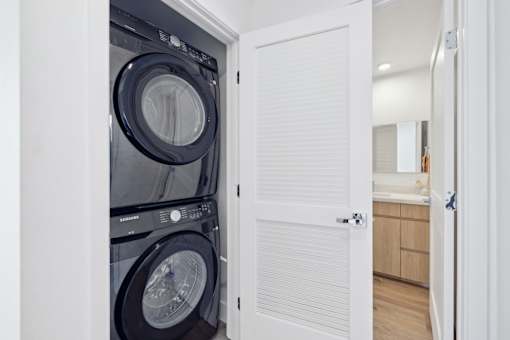 A white door is open to reveal a black washing machine.