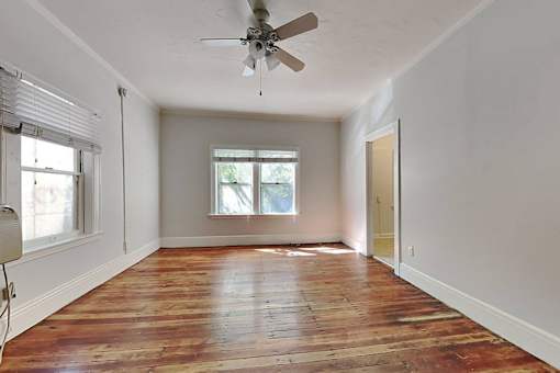 A room with a ceiling fan and wooden flooring.