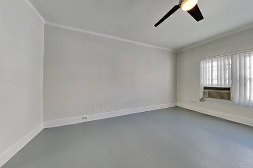 A room with a ceiling fan and a window with blinds.