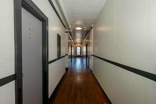 A long hallway with a door on the left and a window on the right.