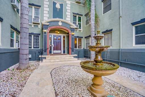 A fountain in front of a building with a red door.