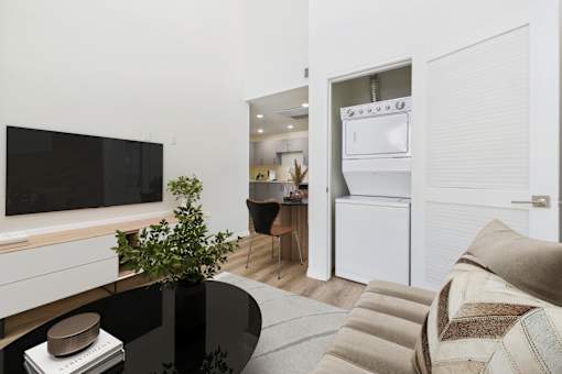 A black table with a plant on it and a white fridge in the background.