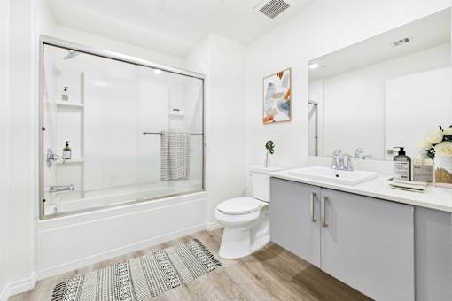 A white bathroom with a glass shower door and a white toilet.