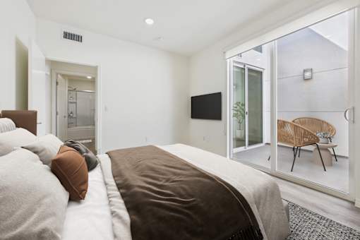 A bedroom with a large bed and a television on the wall.