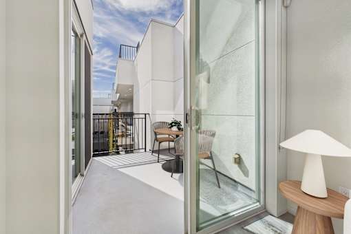 A white lamp sits on a table in a room with a glass door.