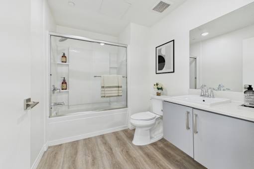 A white bathroom with a toilet, sink, and shower.