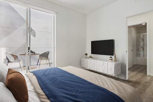 A bedroom with a bed, a chair, a television, and a window.