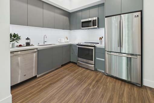 A modern kitchen with stainless steel appliances and wooden flooring.