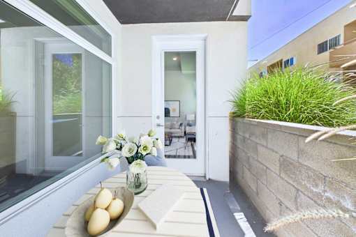 A white door is open to a patio with a table and chairs.