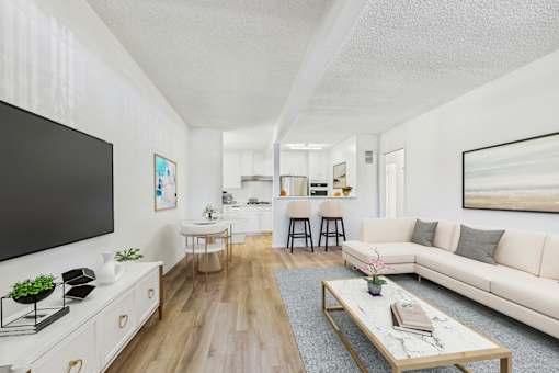 A living room with a white couch, a coffee table, and a television.