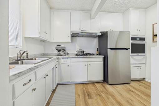 A kitchen with white cabinets and a stainless steel refrigerator.
