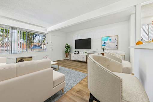 A living room with a white couch, a white chair, a white coffee table, a white fireplace, a white TV, and a white wall.