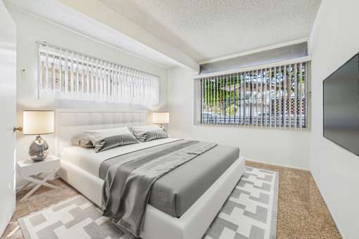 A bedroom with a large bed and a window with blinds.