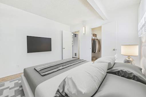 A bedroom with a large bed and a flat screen TV mounted on the wall.