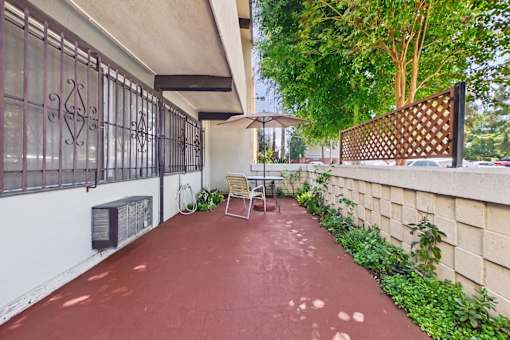 A patio with a red floor and a white wall with a black gate.