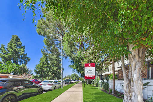 A sign for a Valley Terrace Apartment Complex is displayed on a street.