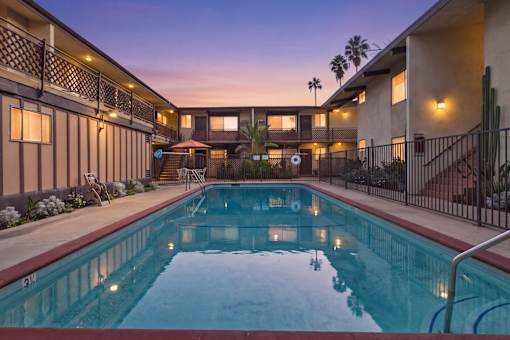A swimming pool in a residential area with a sunset in the background.