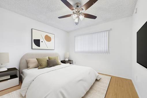 A bedroom with a bed, nightstand, and a ceiling fan.