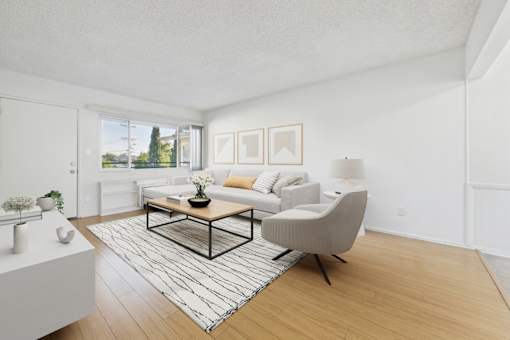 A living room with a white couch, a coffee table, and a chair.