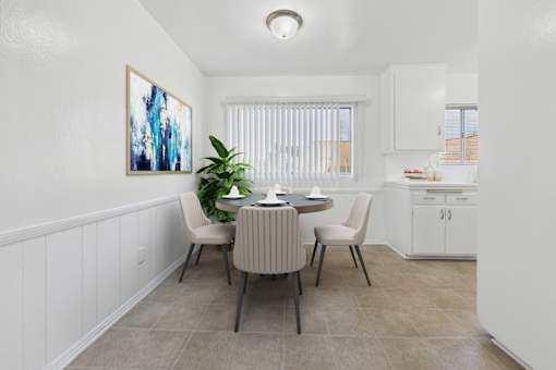 A dining room with a table set for two and a painting on the wall.