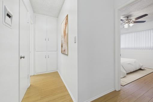 A room with a ceiling fan and a bed in the other room.