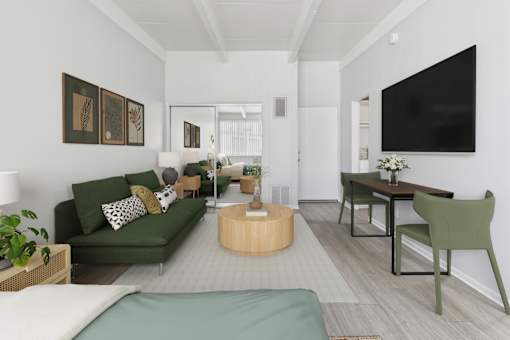 A living room with a green couch and a television on the wall.