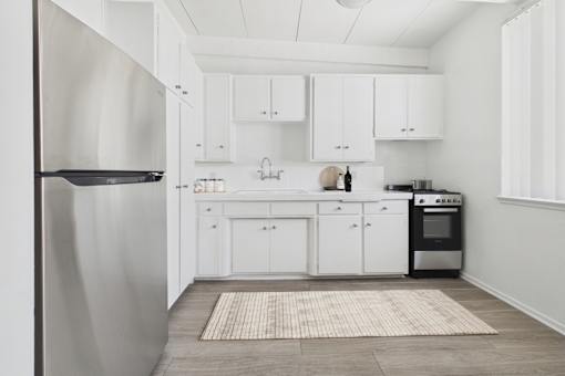 A modern kitchen with white cabinets and a stainless steel refrigerator.