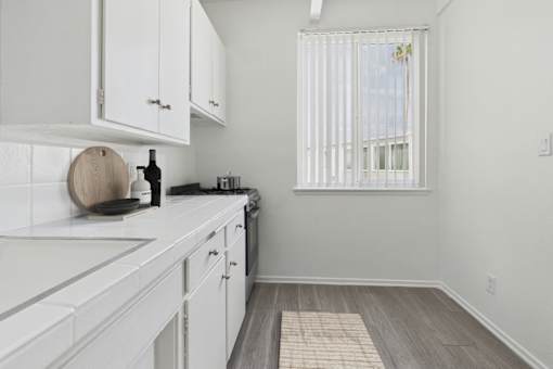 A kitchen with white cabinets and a wooden cutting board on the counter.