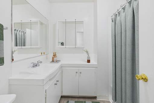 A white bathroom with a sink, mirror, and shower.