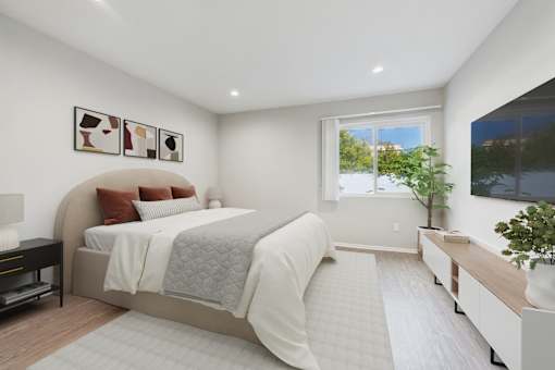 A bedroom with a large bed and a window overlooking a tree.