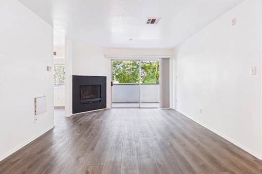 A large empty room with a fireplace and a sliding glass door.