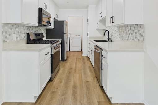 A kitchen with white cabinets and a black fridge.