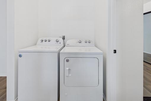 Two white front loading washing machines in a laundry room.