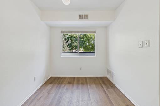 A room with a window and wooden floors.
