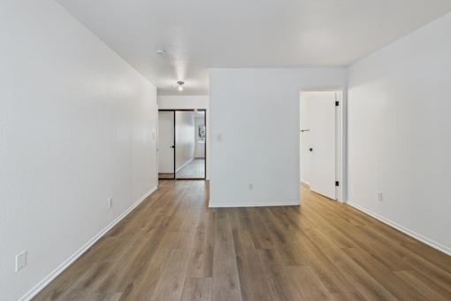 A long, empty room with wood floors and white walls.