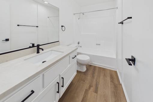 A white bathroom with a toilet, sink, and mirror.