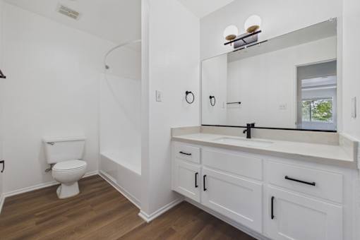 A white bathroom with a toilet, sink, and mirror.
