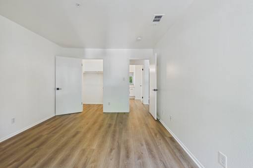 A long hallway with white walls and wood floors.