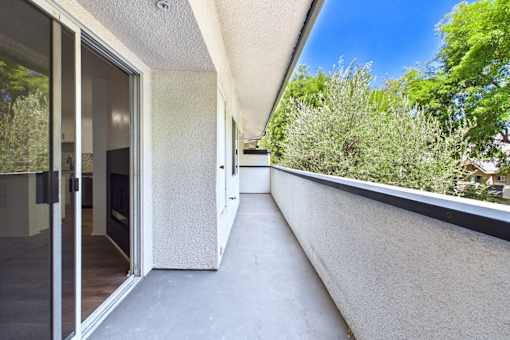A balcony with a glass door leading to a room.