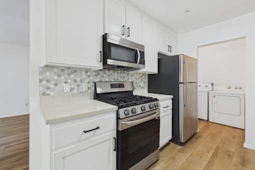 A kitchen with black appliances and white cabinets.