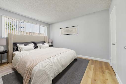 A bedroom with a large bed and a framed picture on the wall.