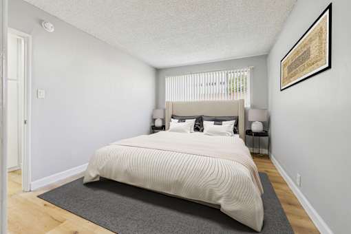 A bedroom with a large bed and a framed picture on the wall.