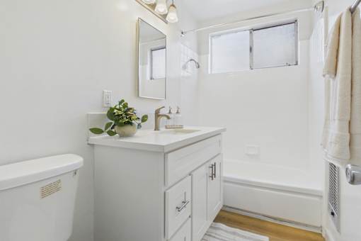 A white bathroom with a tub, sink, mirror, and towel rack.