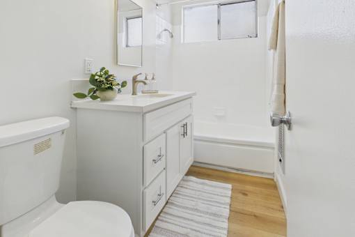 A white bathroom with a toilet, sink, and mirror.