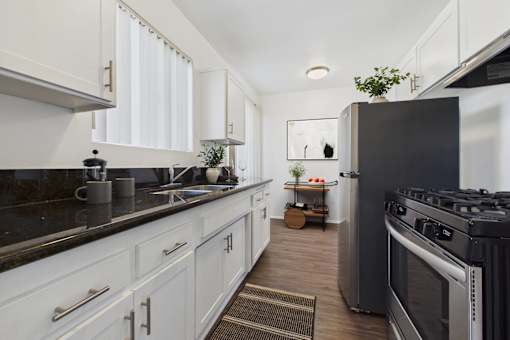 A modern kitchen with white cabinets and black countertops.