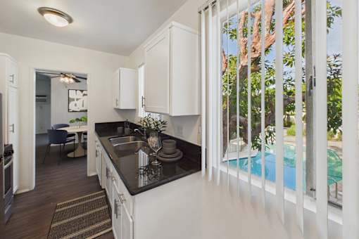 A kitchen with white cabinets and a black countertop.
