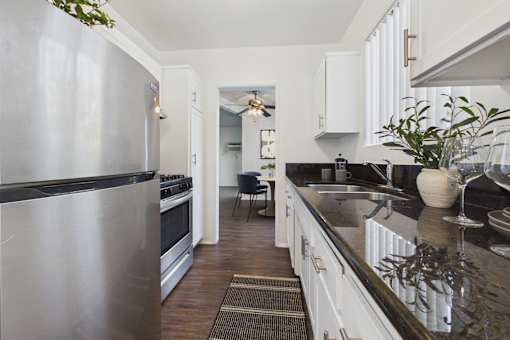 A modern kitchen with a stainless steel refrigerator and black countertops.