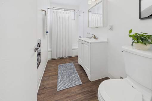 A white bathroom with a toilet, sink, and shower.