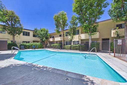 A swimming pool in front of a building with trees.