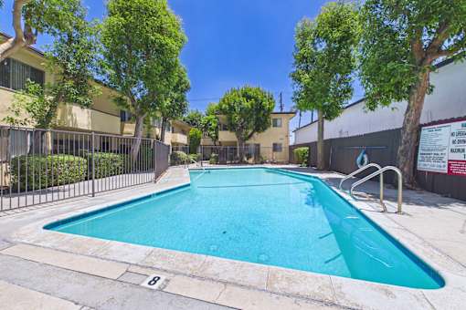 A swimming pool surrounded by a fence and trees.